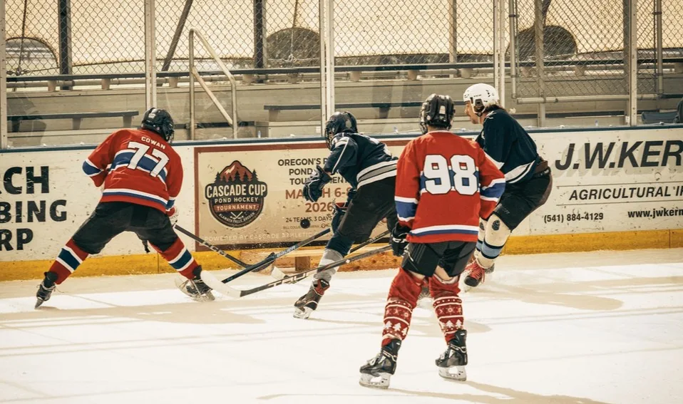 Two skaters chase a loose puck at the 2026 Cascade Cup